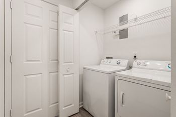A white washer and dryer in a white laundry room with white doors